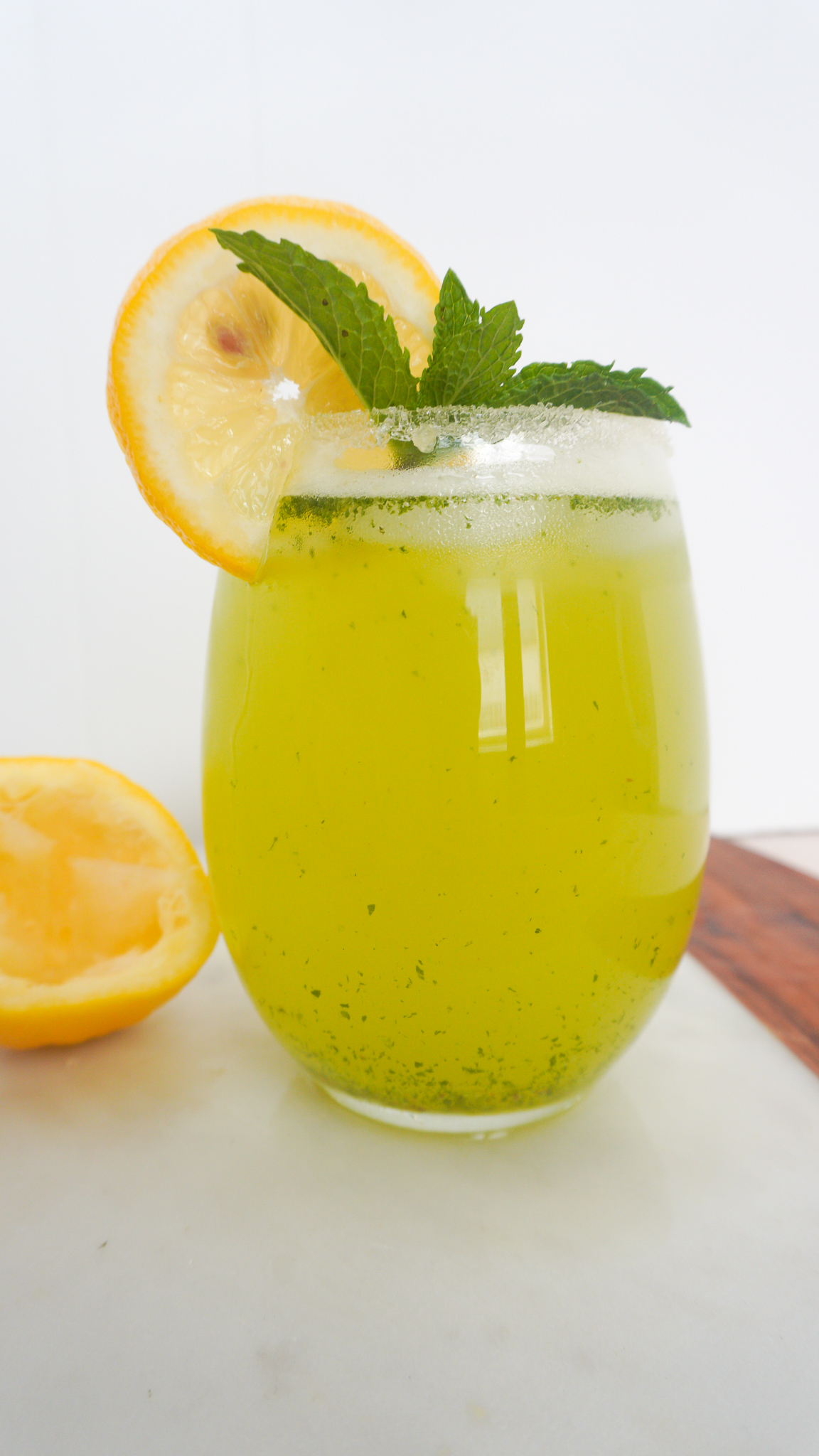 Lemon mint drink in glass with lemon and mint garnish