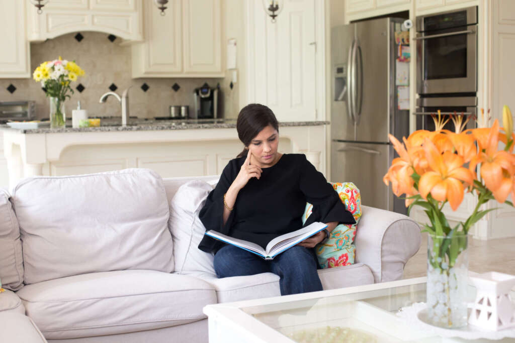 woman sitting on couch, reading a book