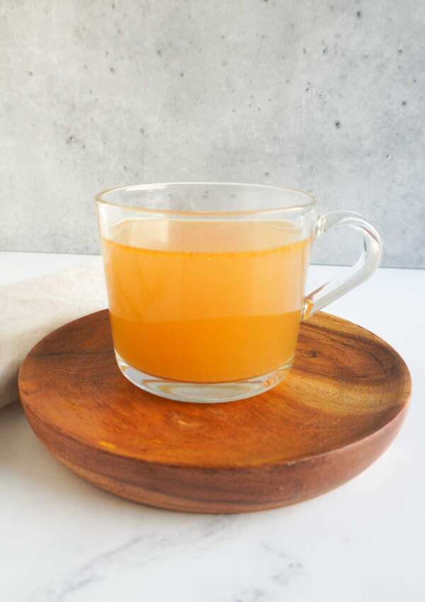 a cup of yakhni on a wooden plate