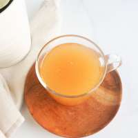 bone broth in a clear cup with a wooden tray