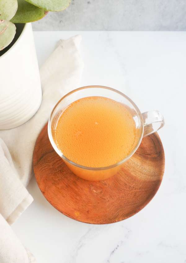 bone broth in a clear cup with a wooden tray