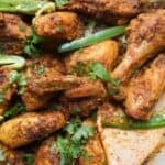 Chicken karahi in a light colored pan with cilantro and green chili garnish.
