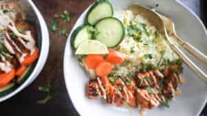 Salmon bowl with cauliflower rice and vegetables and another similar bowl to the left