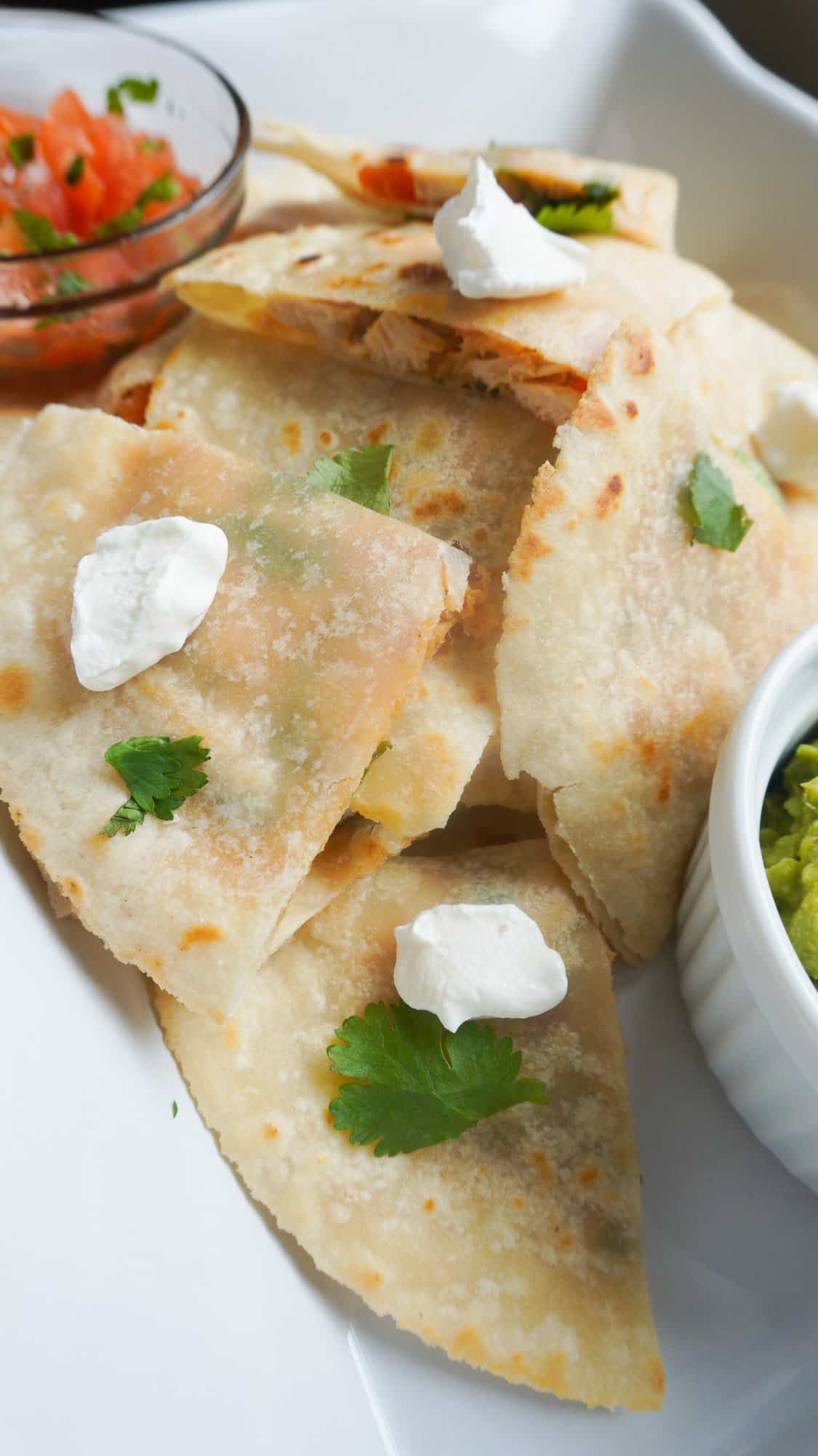 mini chicken quesadillas in a tray with guacamole and salsa condiments