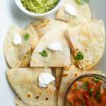 mini chicken quesadillas in a tray with guacamole and salsa condiments