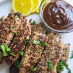 Seekh kababs on a serving platterwith chutney and lemon slices on the side