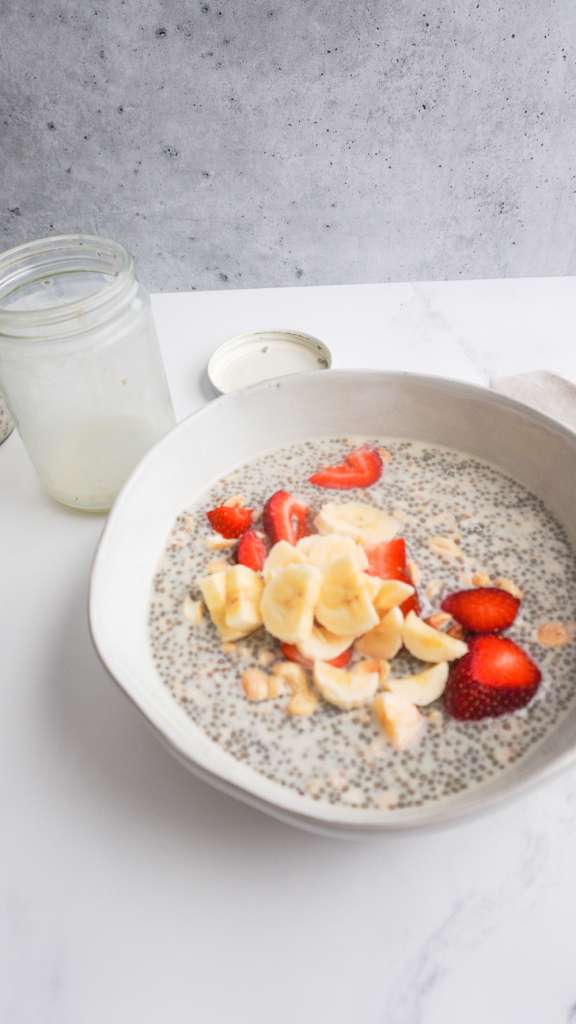 chia and oat cereal in a bowl with strawberries, banana and nuts on top