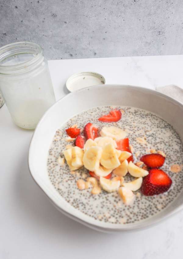 chia and oat cereal in a bowl with strawberries, banana and nuts on top