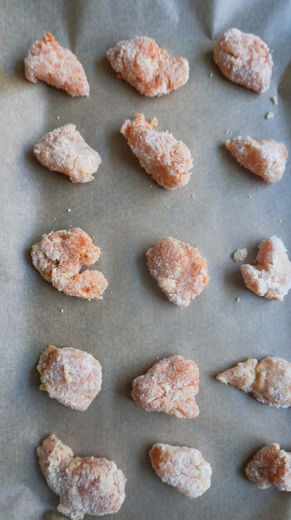 coated chicken nuggets on parchment lined cookie sheet