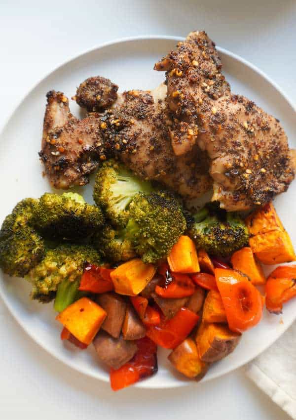 A plate of sumac marinaded chicken thigh and roasted bell peppers, broccoli and sweet potatoes