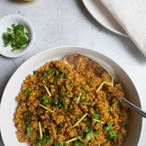 serving bowl of keema and plates, cutlery and napkins