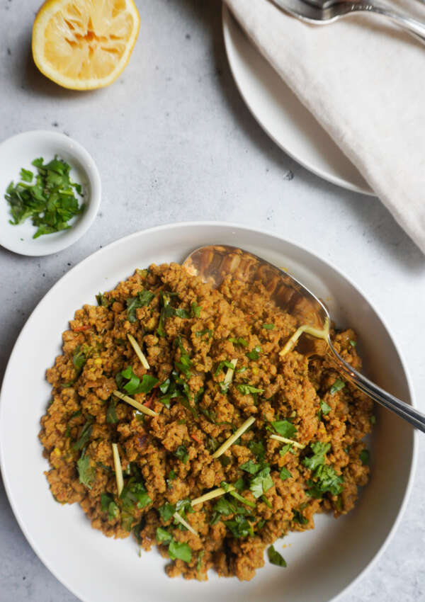 serving bowl of keema and plates, cutlery and napkins