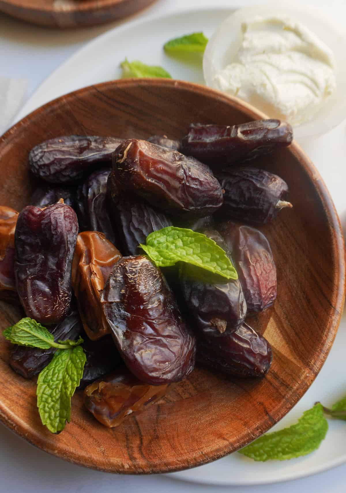 Medjool dates in a wooden bowl with mint leaves