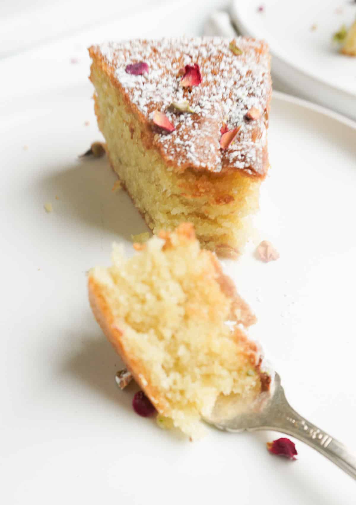 A slice of cardamom cake and one bite sized piece on fork