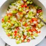A bowl of finely diced tomatoes, onions, green chili and cucumbers. Seasoned with cilantro, lemon juice and salt