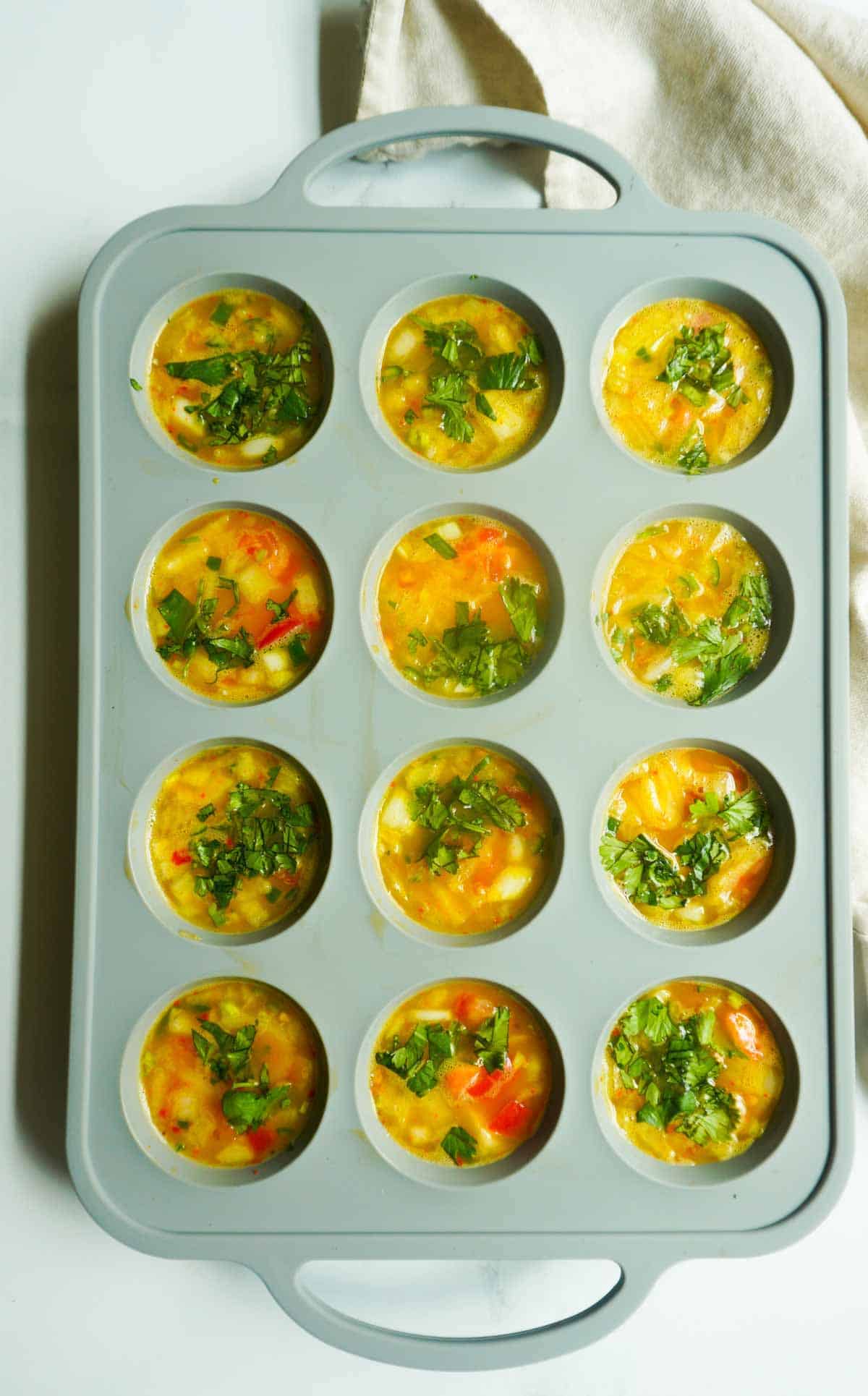 raw spicy egg muffin mix in muffin pan 