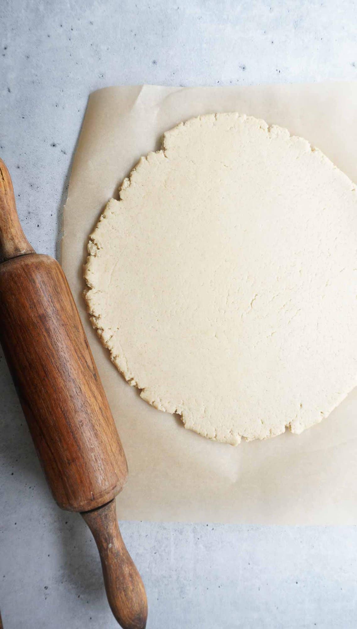 rolled out barley dough on parchment paper and a rolling pin 