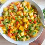 chopped mango, nectarine, cucumber and strawberries in a bowl with mint garnish. Squeezed lemon to the side and mint sprig
