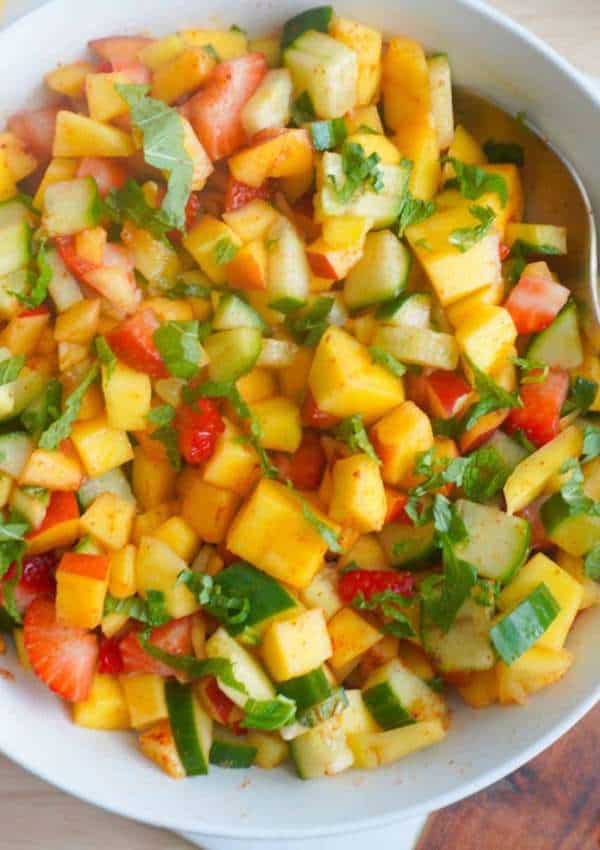 chopped mango, nectarine, cucumber and strawberries in a bowl with mint garnish. Squeezed lemon to the side and mint sprig