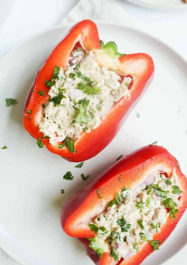 2 halves of red bell pepper stuffed with tuna salad on a plate