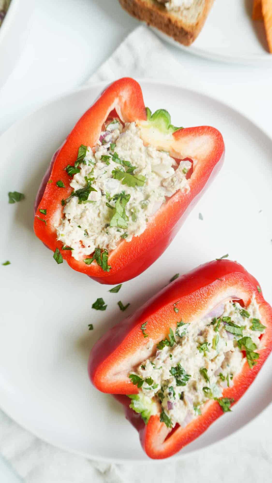 2 halves of red bell pepper stuffed with tuna salad on a plate