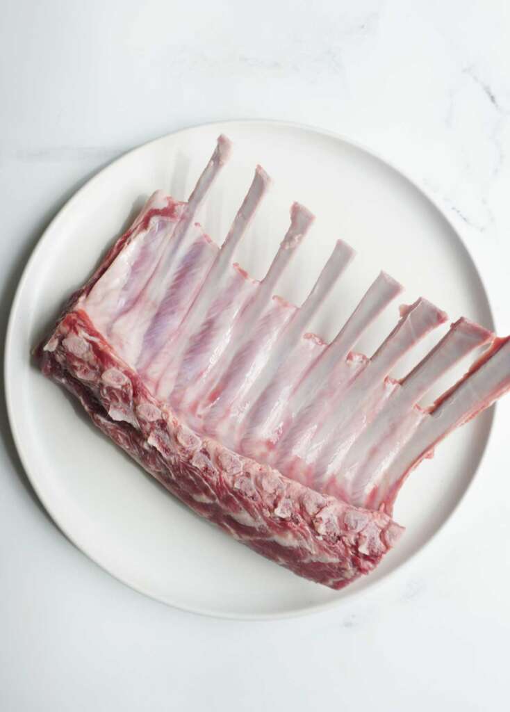 Frenched rack of lamb on a white plate.