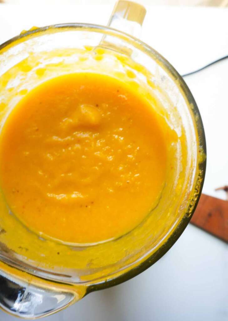 A blender with blended pumpkin soup