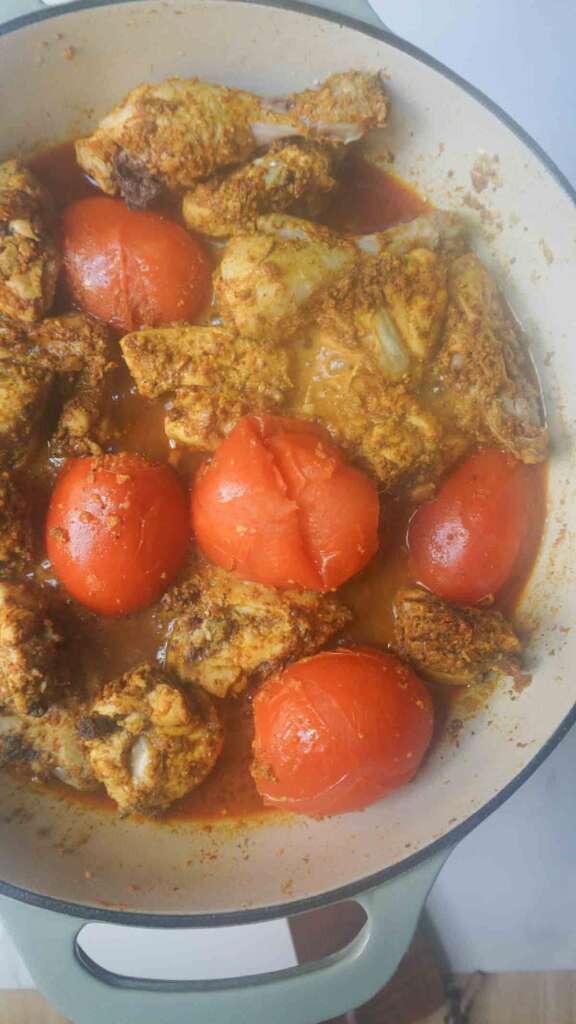 Karahi Chicken cooking in pan with whole tomatoes