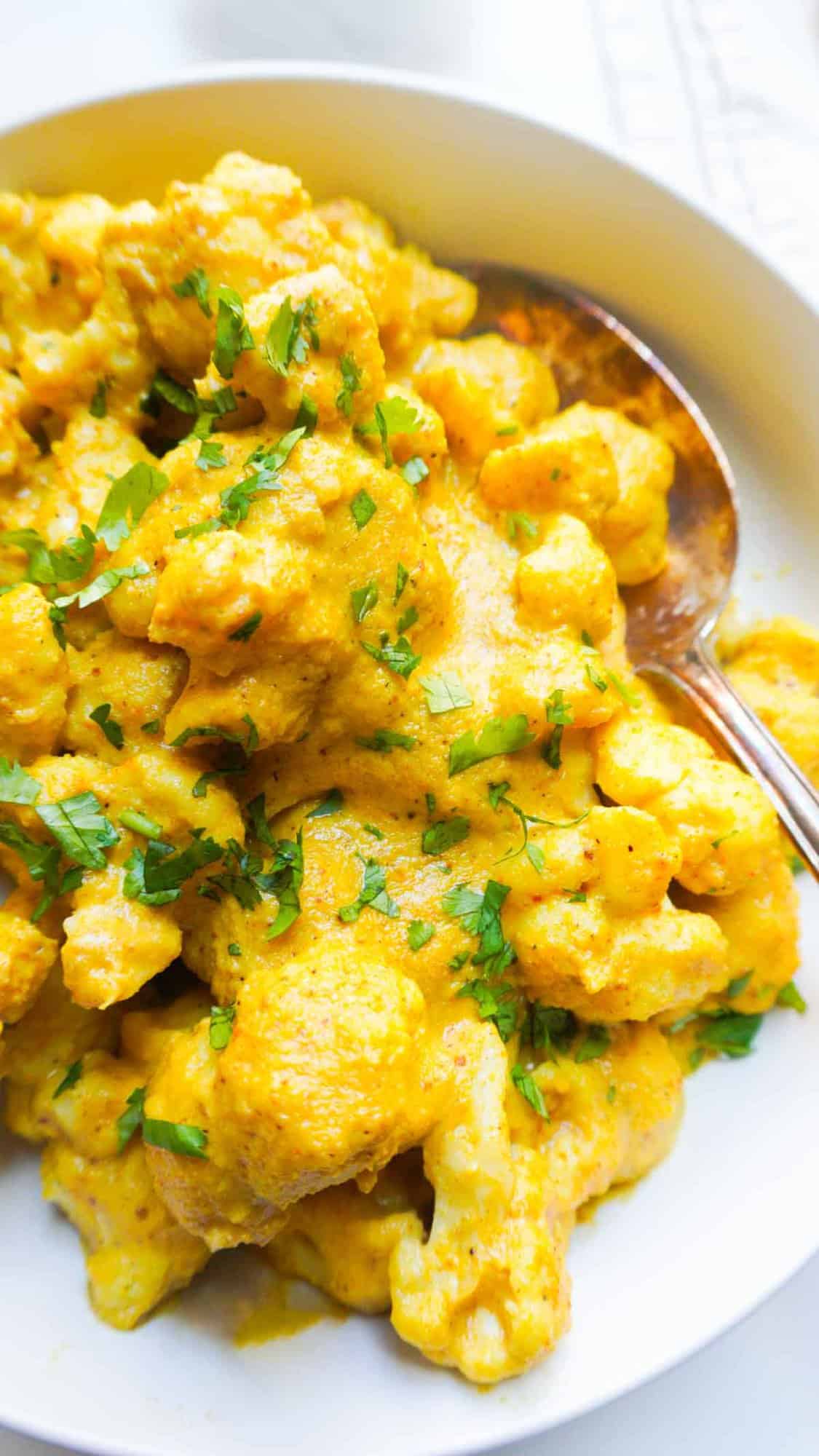 cauliflower cashew sauce/curry in a bowl with serving spoon