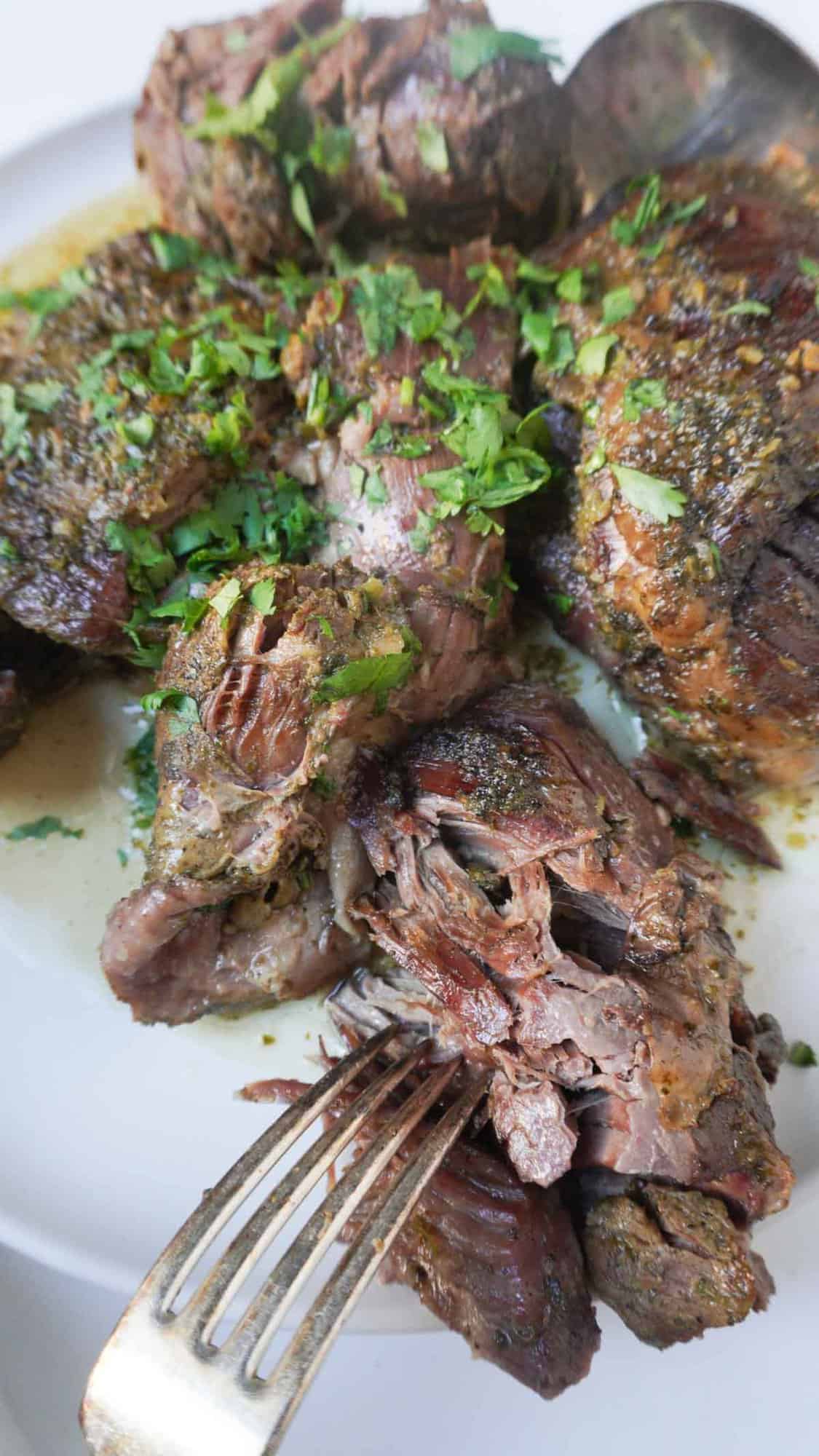 Slow cooked leg of lamb/mutton on a serving platter with a fork