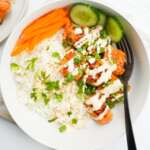 close up of a spicy, crispy salmon tikka bowl with carrot ribbons, cucumber slices and spicy mayo drizzle