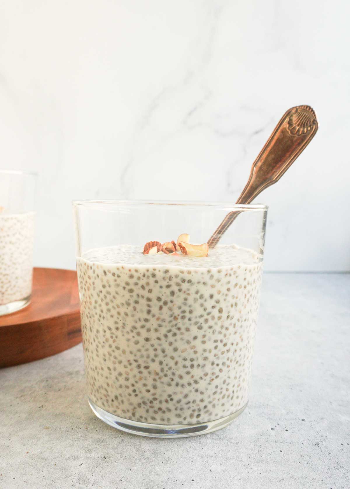 A clear glass cup of chia kheer with a spoon and another one in the background