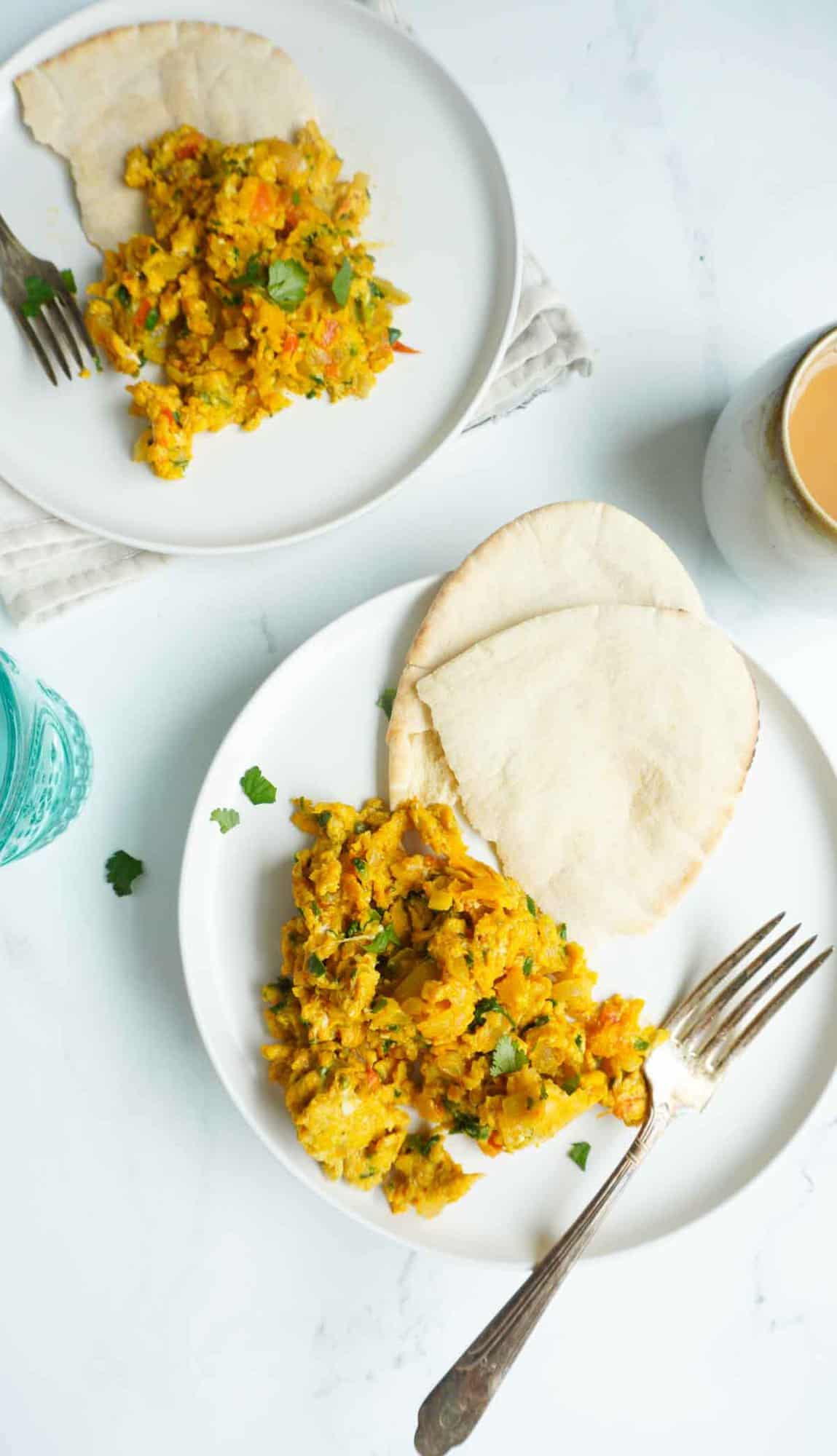 2 plates of khagina with pita bread and forks. A tea mug off to the side.