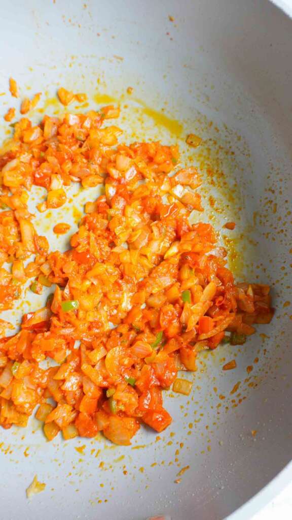 Sauted onions, tomatoes and green chilies with spices in pan.