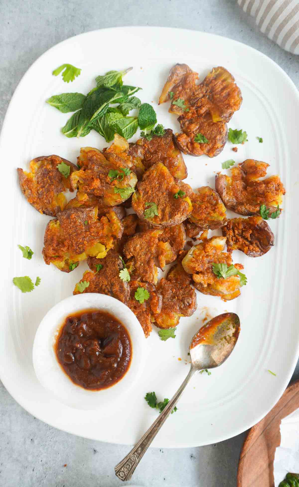 A platter with baked aloo pakoras and a bowl of imli ki chutney