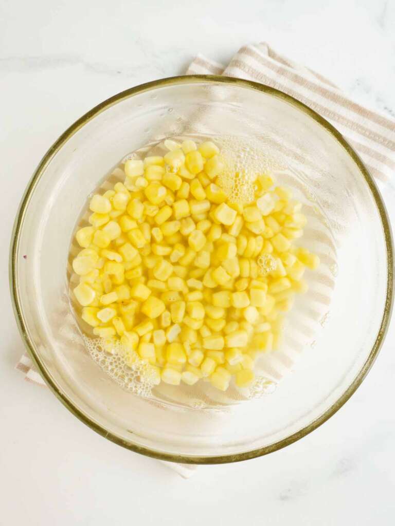 a clear bowl with corn and water