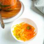 A bowl of quick pickled carrots and a filled jar in the background