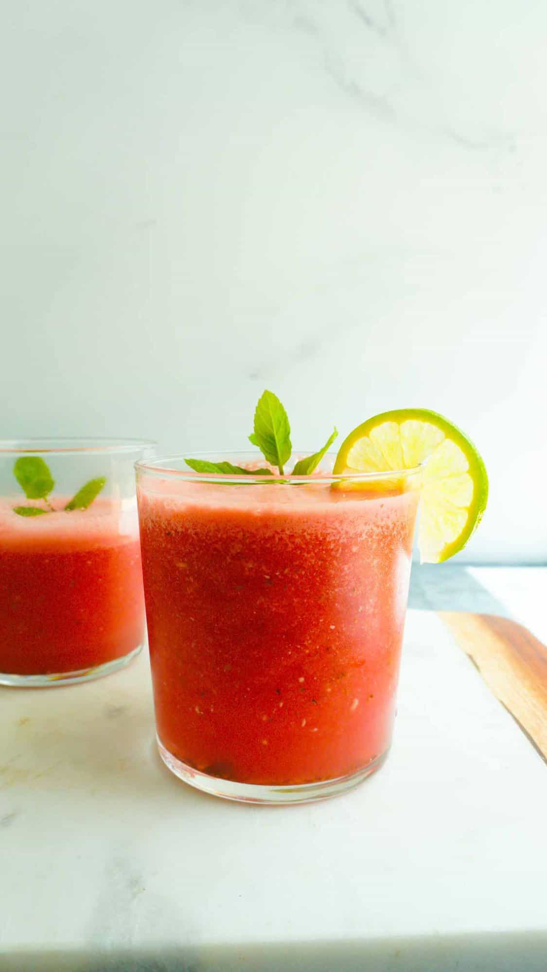 2 glasses of watermelon juice with lime and mint garnish