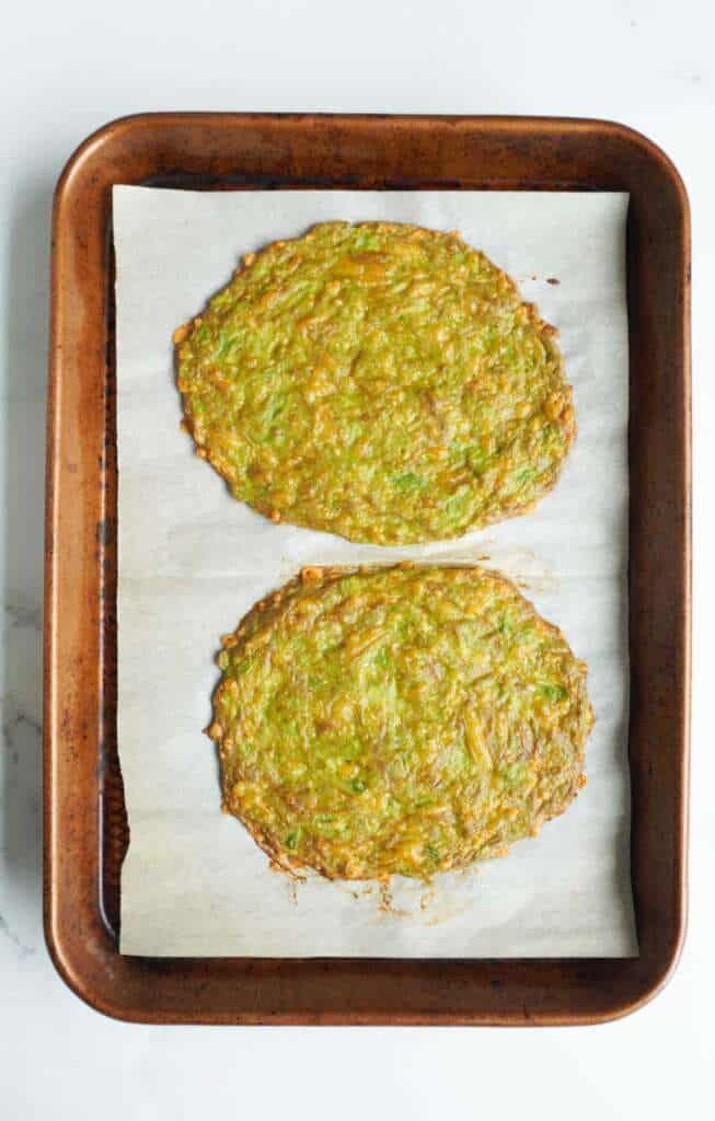 Two baked avocado bread discs on cookie sheet