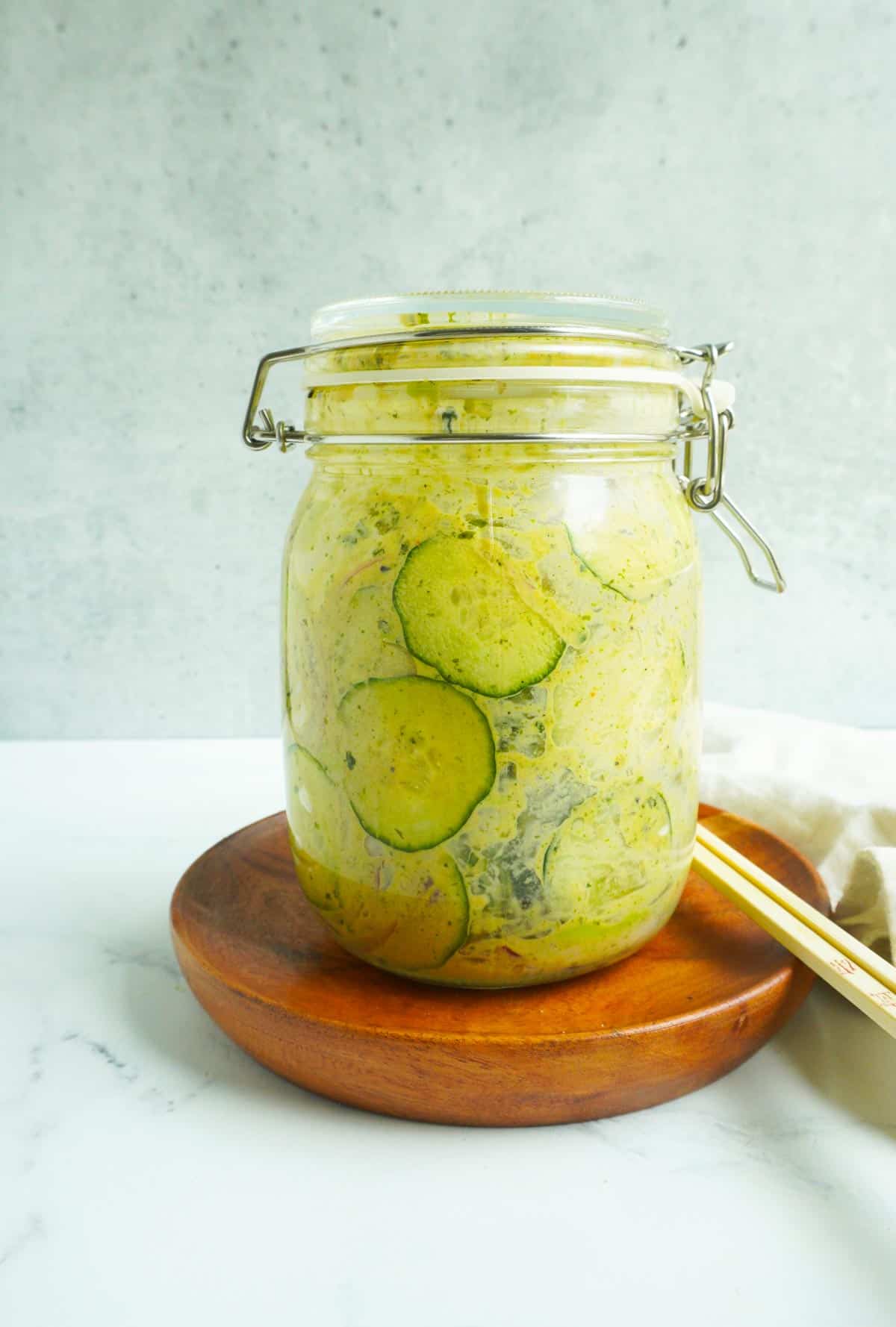 A glass jar with cucumbers and dressing inside