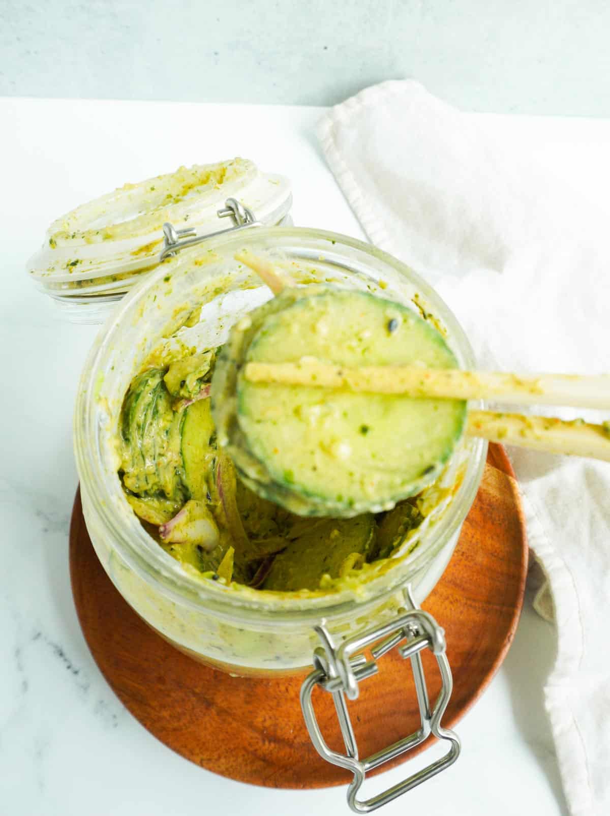 chopsticks with cucumbers over a jar of viral cucumber salad