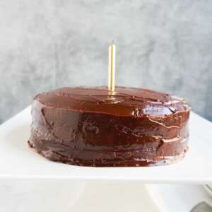 An almond flour cake with a candle on a cake pedestal