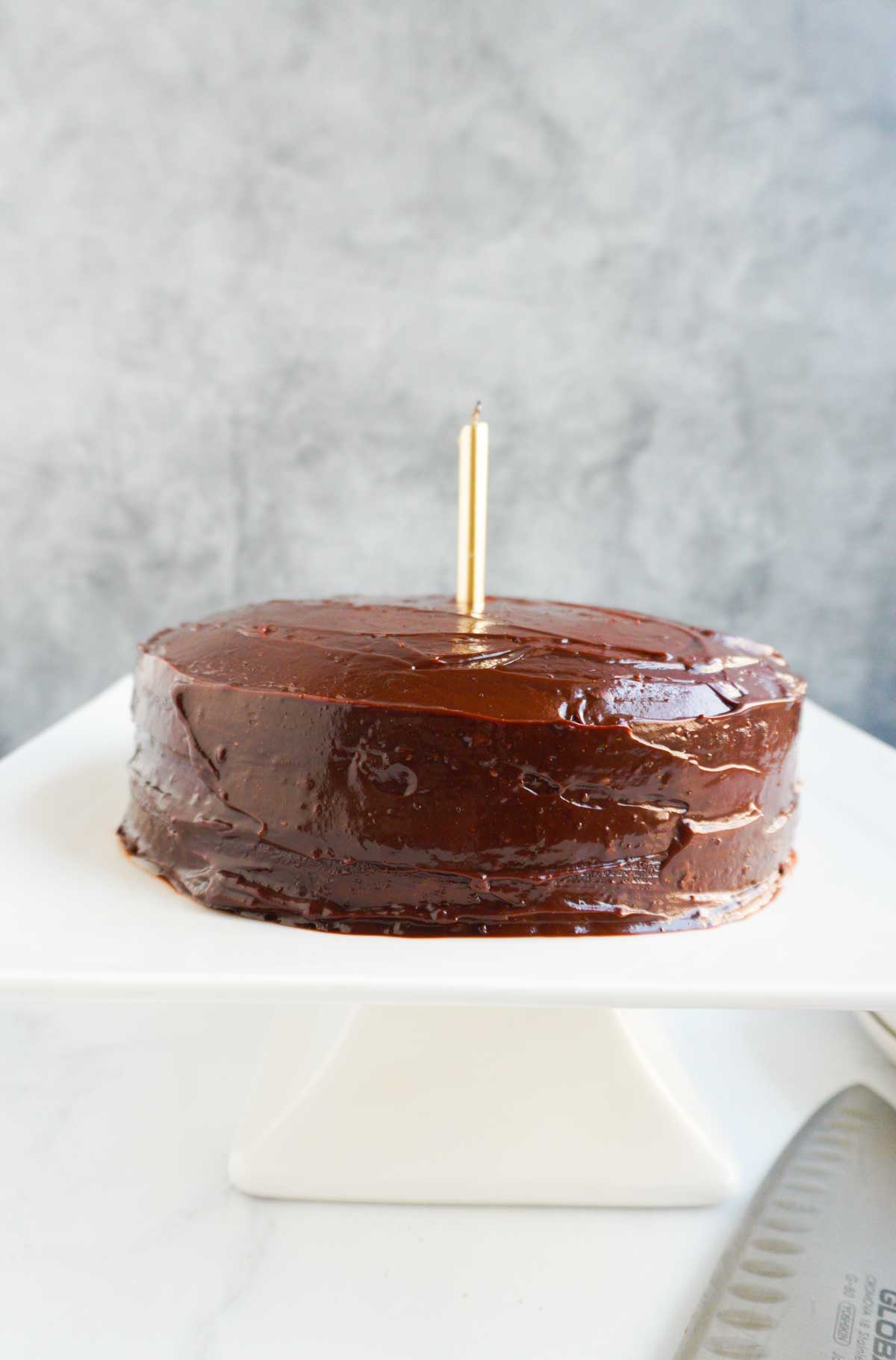 An almond flour cake with a candle on a cake pedestal