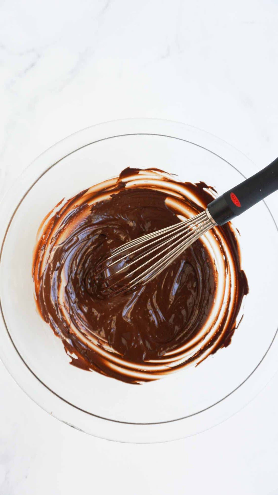 melted chocolate in glass bowl with a whisk.
