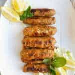 Chicken Seekh Kebabs on a platter with lemon wedges and mint garnish
