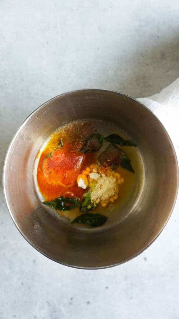 spices, gram flour and curry leaves in a saucepan