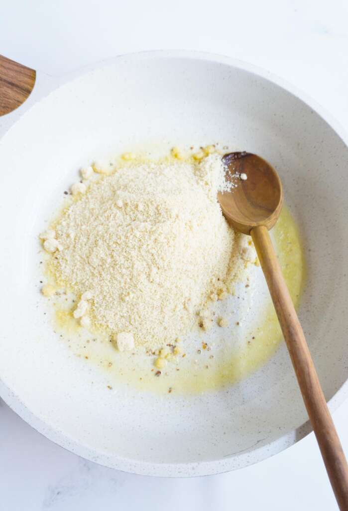 almond flour and butter in pan with a wooden spoon on the side 
