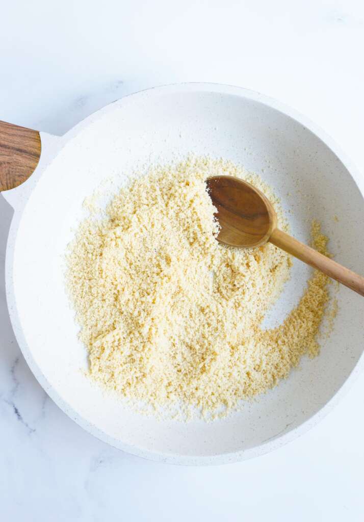 toasted almond flour in pan with a wooden spoon
