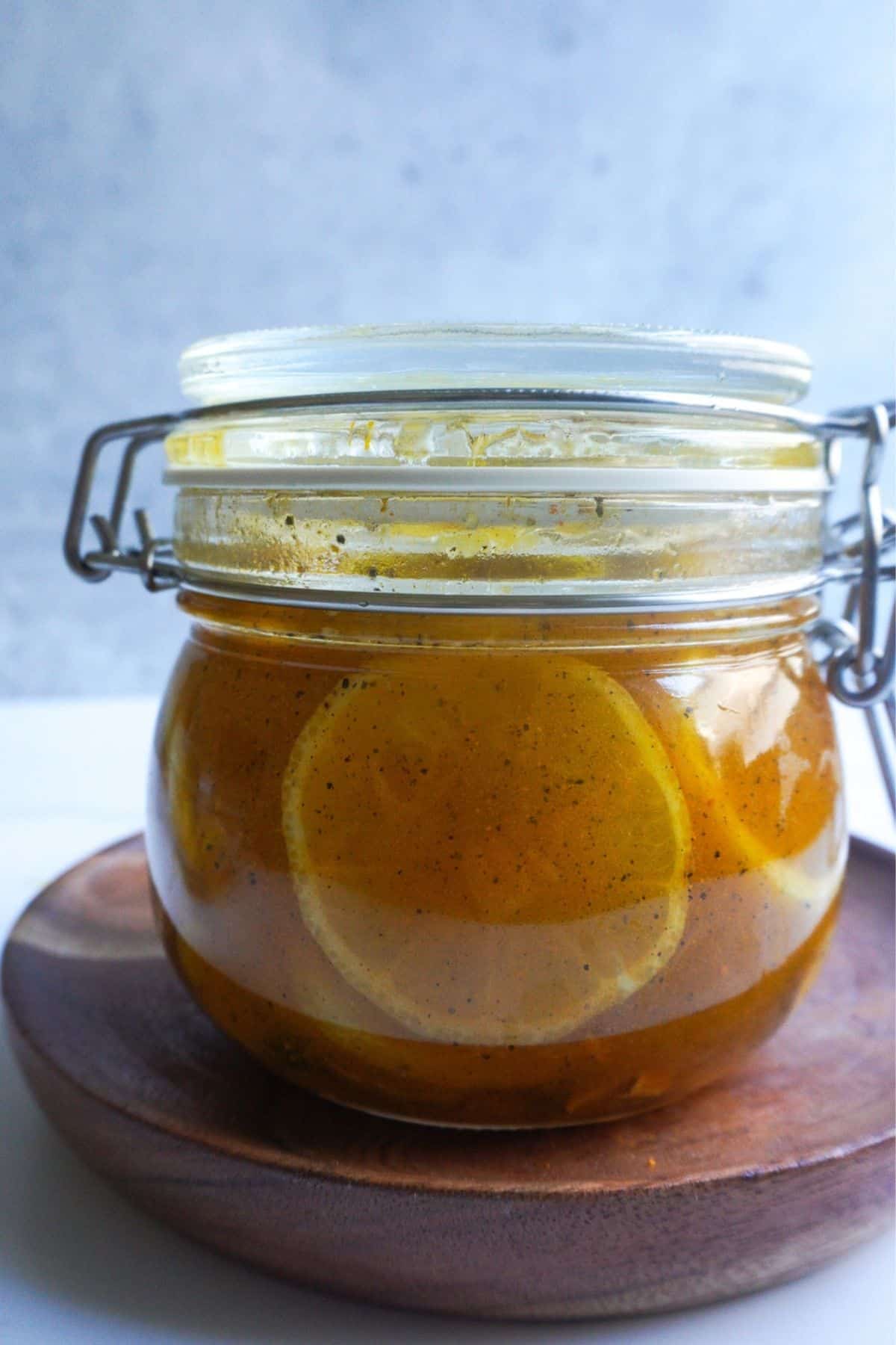 A closed glass jar with honey lemon syrup on a wooden plate.