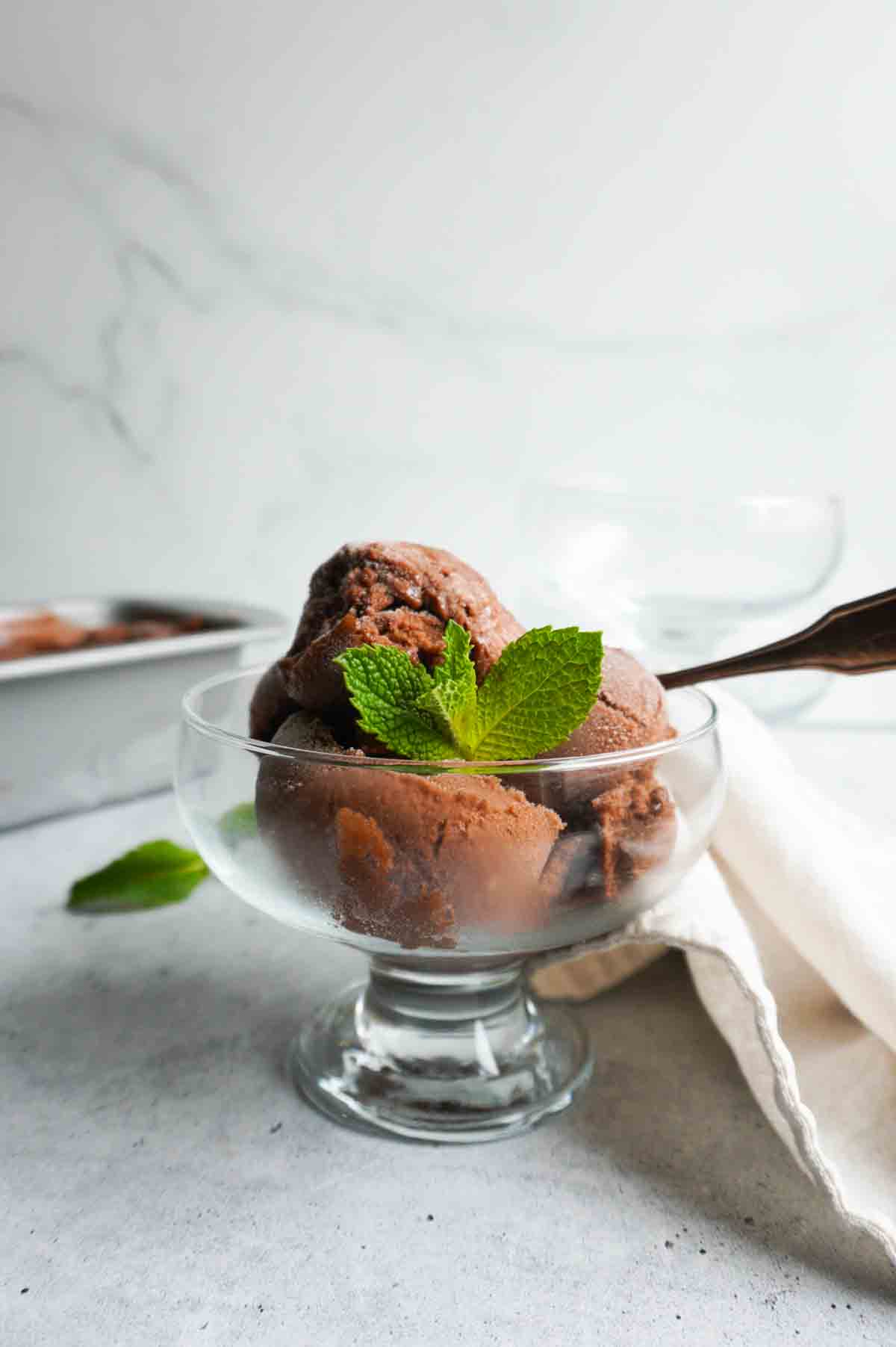 Chocolate banana nice cream in a glass bowl with a spoon.